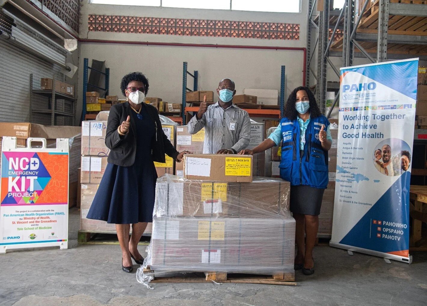 three people wearing masks posing in a distribution centre