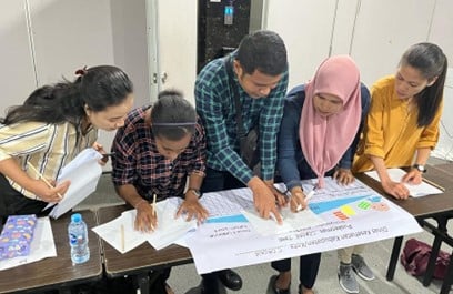 5 people standing and pointing at a graph on a table.