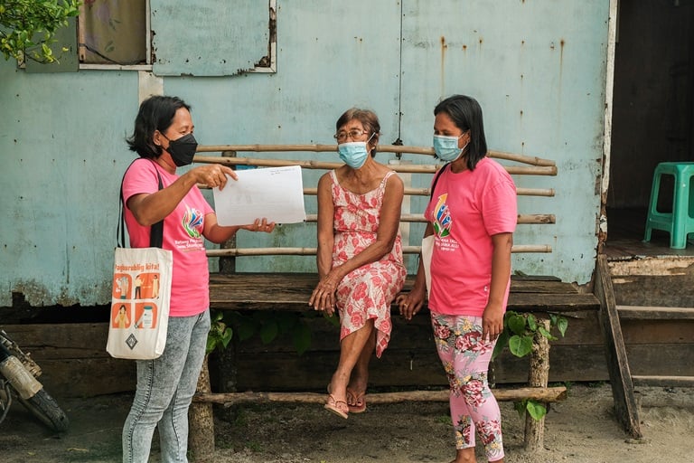 Barangay Health Worker Lorena Ida (left) shares the benefits of COVID-19 vaccines to a senior citizen in Manicani Island, Eastern Samar.